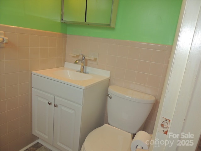 bathroom featuring vanity, toilet, and tile walls