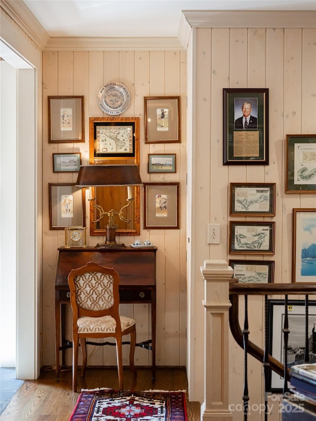 sitting room with hardwood / wood-style flooring, ornamental molding, and wooden walls