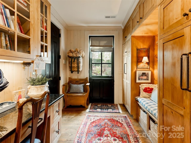 mudroom with wood walls, light hardwood / wood-style floors, and crown molding