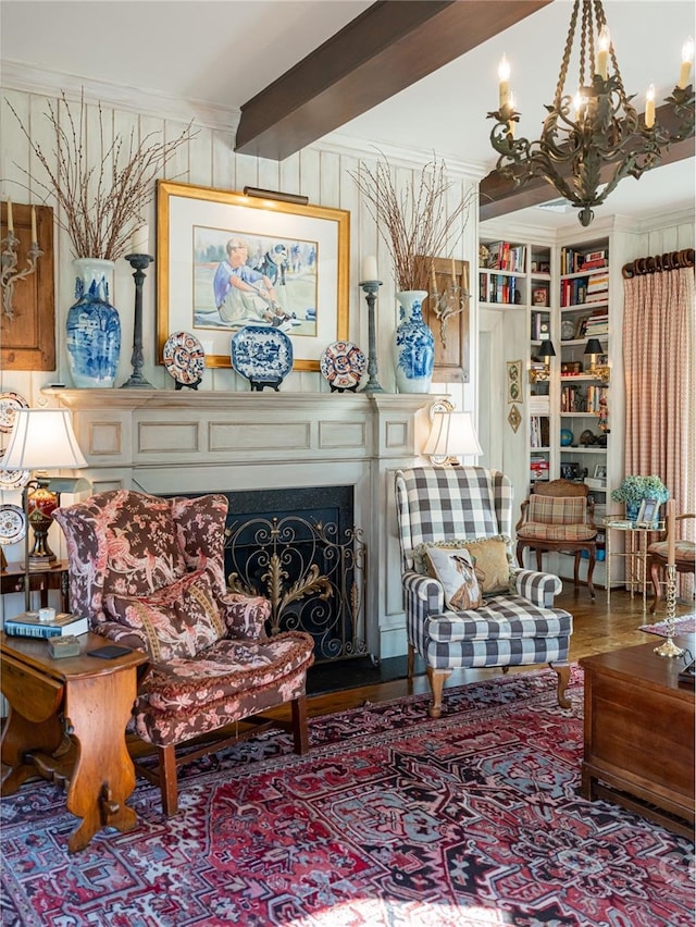 sitting room featuring wood-type flooring, built in features, ornamental molding, and an inviting chandelier