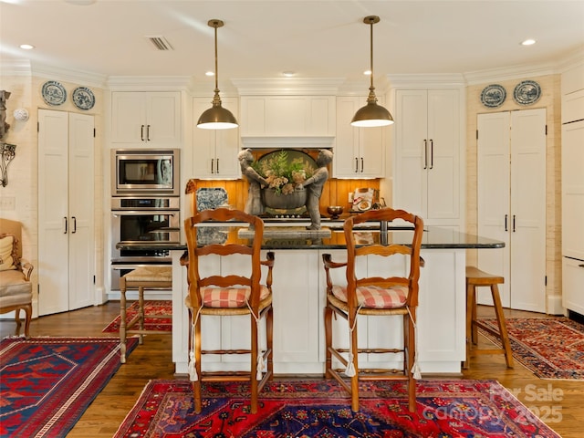 kitchen featuring a kitchen bar, pendant lighting, a center island, and stainless steel appliances