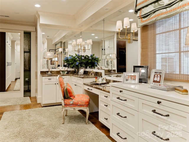 interior space with white cabinetry, dark wood-type flooring, hanging light fixtures, light stone counters, and crown molding