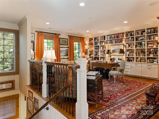 living area featuring built in features, wood-type flooring, and ornamental molding