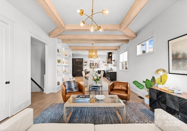 living room with built in features, beamed ceiling, wood-type flooring, and an inviting chandelier