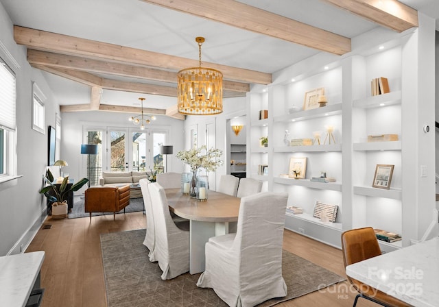 dining area featuring a chandelier, french doors, built in features, and beam ceiling