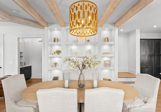 dining area with hardwood / wood-style floors, beam ceiling, built in features, and a chandelier