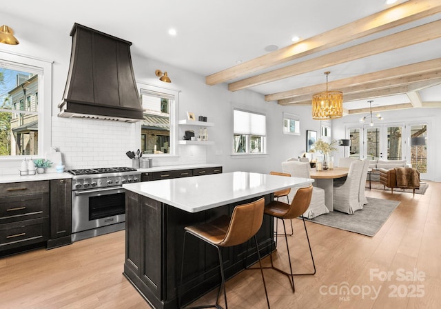 kitchen featuring custom exhaust hood, high end stove, tasteful backsplash, decorative light fixtures, and a kitchen island