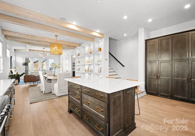 kitchen featuring a center island, french doors, decorative light fixtures, beam ceiling, and dark brown cabinetry