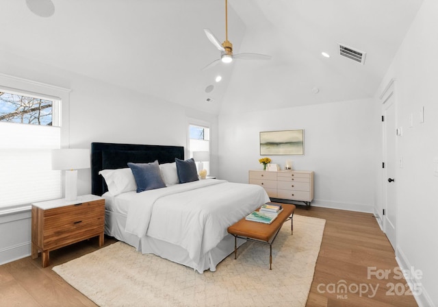 bedroom featuring multiple windows, ceiling fan, lofted ceiling, and light wood-type flooring