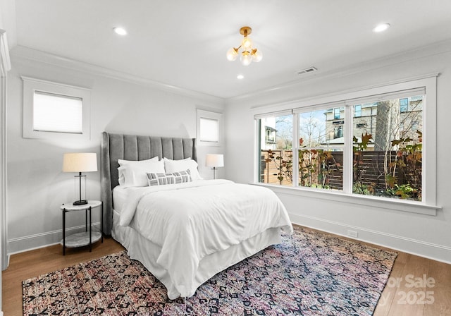 bedroom with a chandelier, wood-type flooring, multiple windows, and crown molding