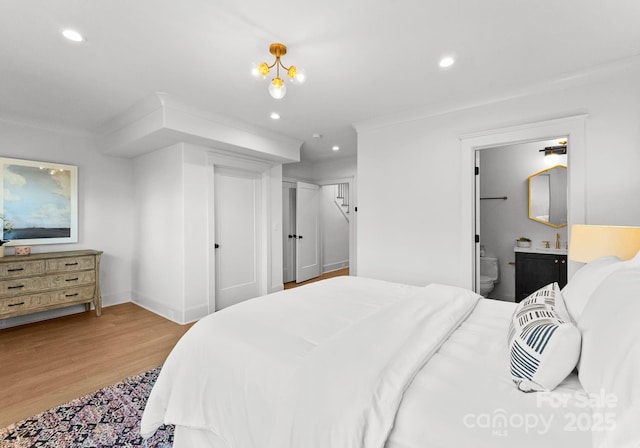 bedroom with light hardwood / wood-style floors, ornamental molding, and ensuite bath