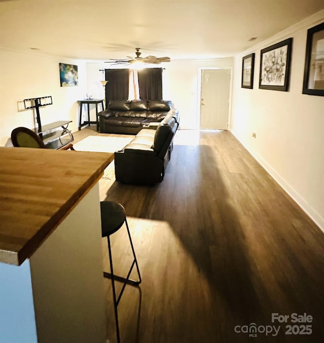 living room featuring hardwood / wood-style floors, ceiling fan, and ornamental molding