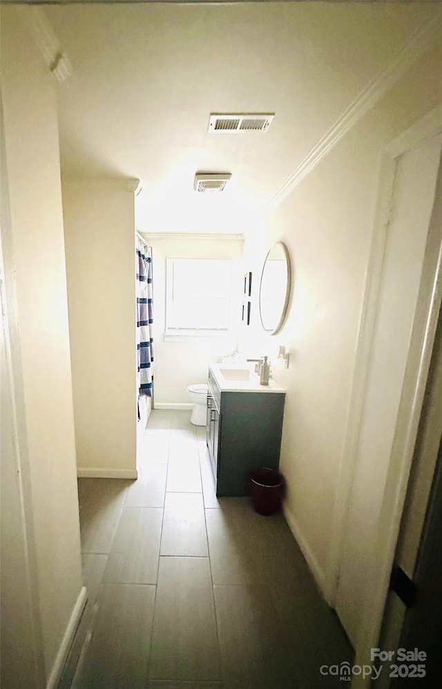 bathroom with vanity, toilet, and ornamental molding