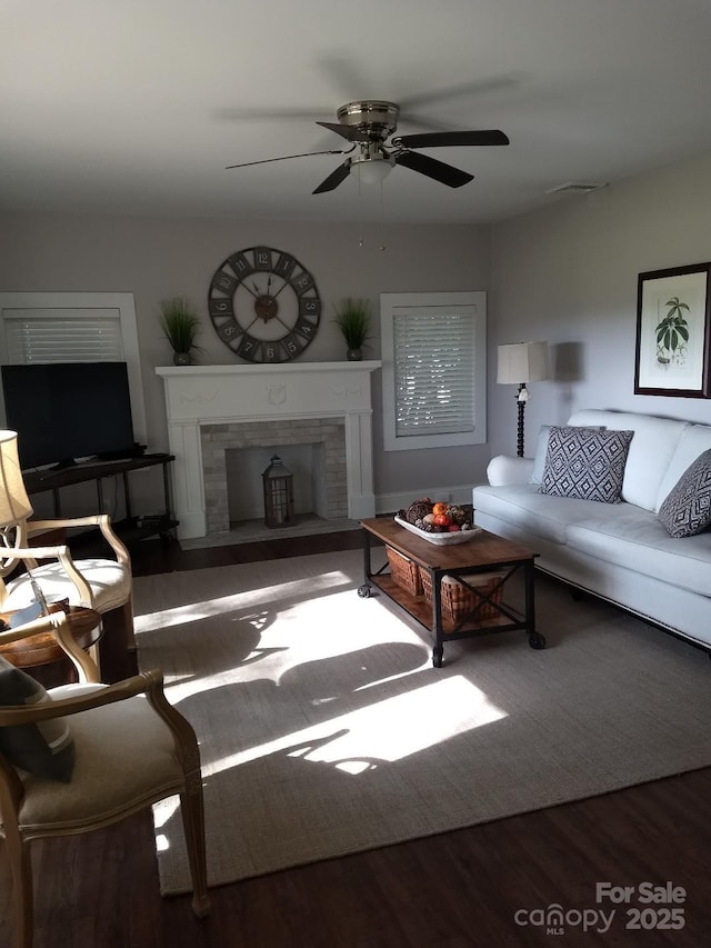 living room featuring wood-type flooring, ceiling fan, and a tiled fireplace