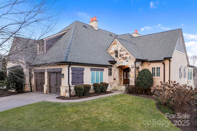 french country inspired facade featuring a front lawn and a garage