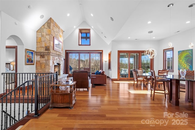 interior space featuring a fireplace, light wood-type flooring, a chandelier, and high vaulted ceiling