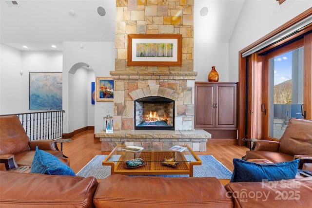 living room featuring light wood-type flooring, a fireplace, and vaulted ceiling