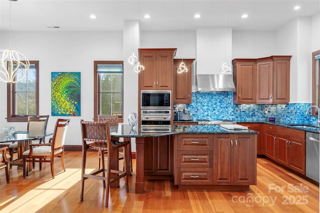 kitchen with a center island, sink, dark stone countertops, stainless steel appliances, and extractor fan