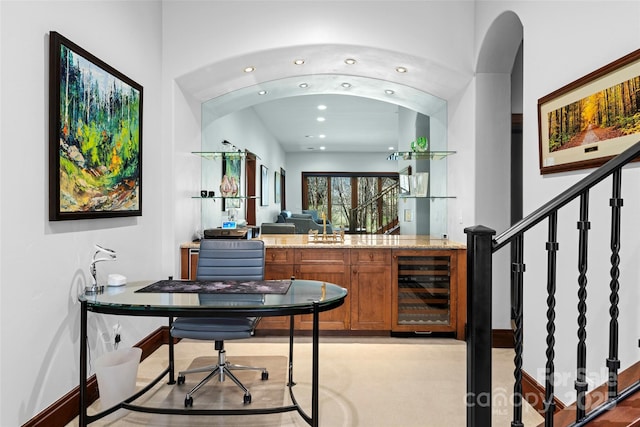 bar featuring light stone countertops, wine cooler, and sink