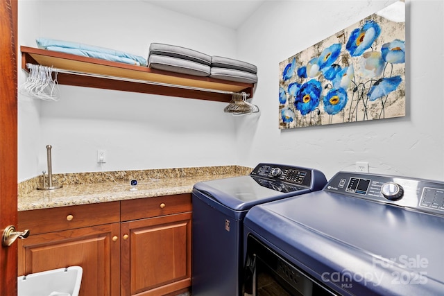 clothes washing area featuring cabinets and washer and dryer