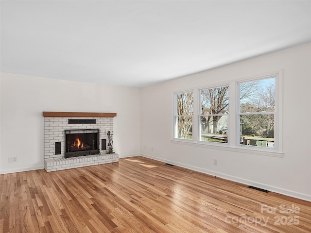 unfurnished living room with light hardwood / wood-style flooring and a brick fireplace