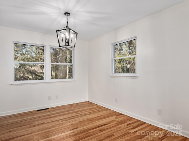 unfurnished dining area featuring hardwood / wood-style floors and a chandelier