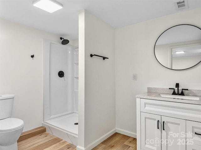 bathroom with hardwood / wood-style flooring, vanity, toilet, and walk in shower