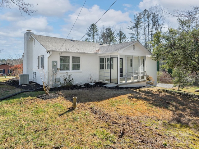 view of front of home with central air condition unit, a sunroom, and a front yard