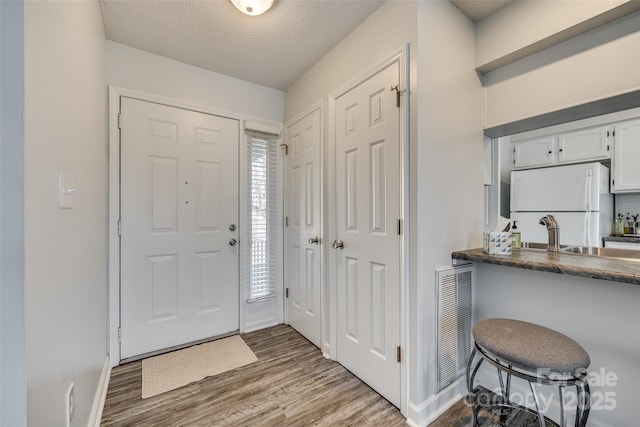 entrance foyer with a textured ceiling, light hardwood / wood-style flooring, and sink