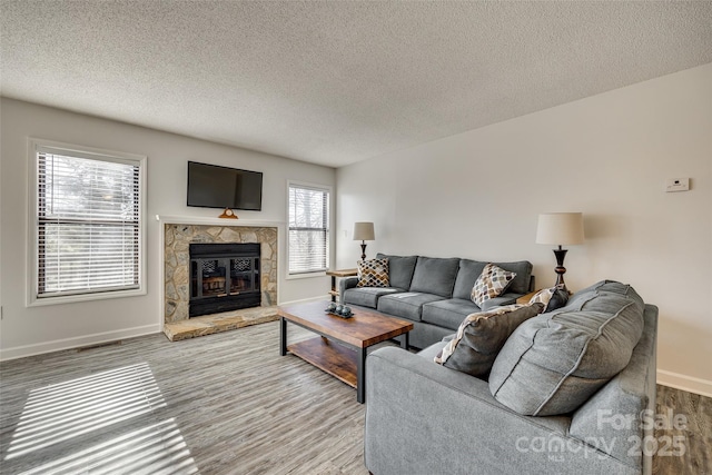 living room featuring a tile fireplace, a textured ceiling, a wealth of natural light, and hardwood / wood-style floors