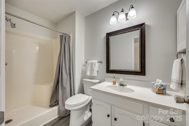 bathroom with a textured ceiling, hardwood / wood-style flooring, toilet, walk in shower, and vanity