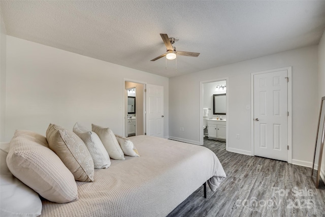 bedroom with a textured ceiling, connected bathroom, ceiling fan, and dark hardwood / wood-style floors