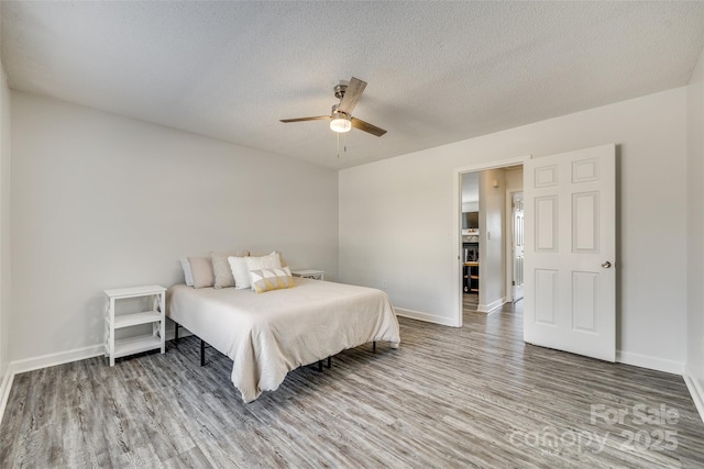 bedroom featuring hardwood / wood-style floors, a textured ceiling, and ceiling fan