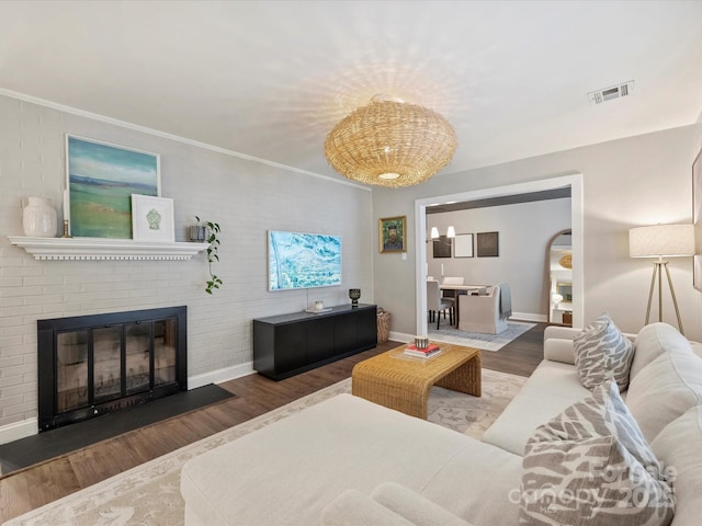 living room featuring crown molding, wood-type flooring, and a fireplace