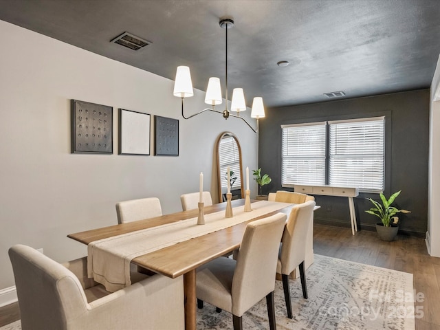 dining space with hardwood / wood-style floors and a notable chandelier