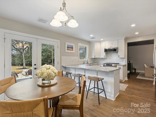 dining space with hardwood / wood-style flooring, sink, and french doors