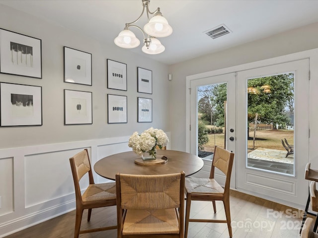 dining room with a notable chandelier, wood-type flooring, and french doors