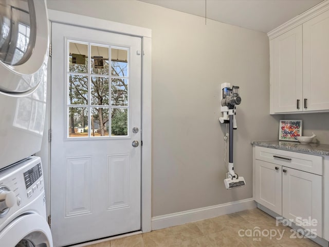 laundry area featuring cabinets, stacked washer and dryer, and light tile patterned floors