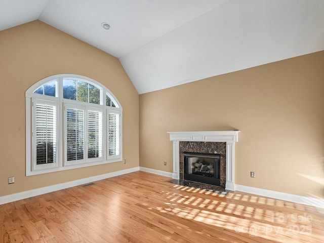 unfurnished living room with a fireplace, light hardwood / wood-style floors, and vaulted ceiling