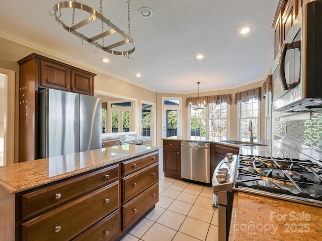 kitchen with pendant lighting, sink, ornamental molding, and stainless steel appliances