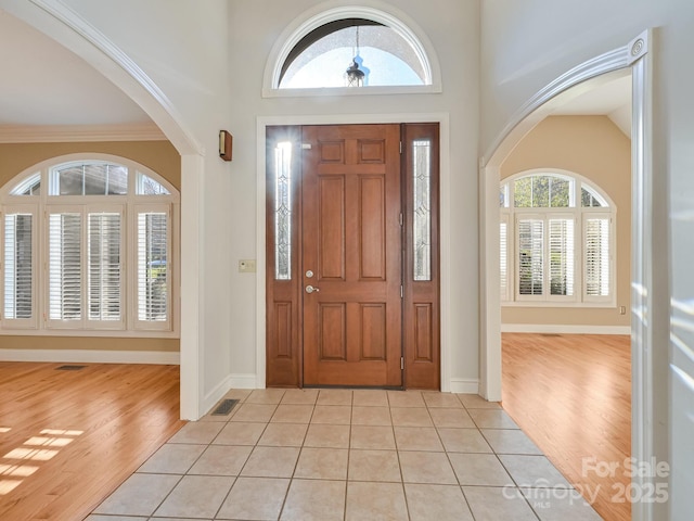 foyer entrance with light tile patterned floors and crown molding