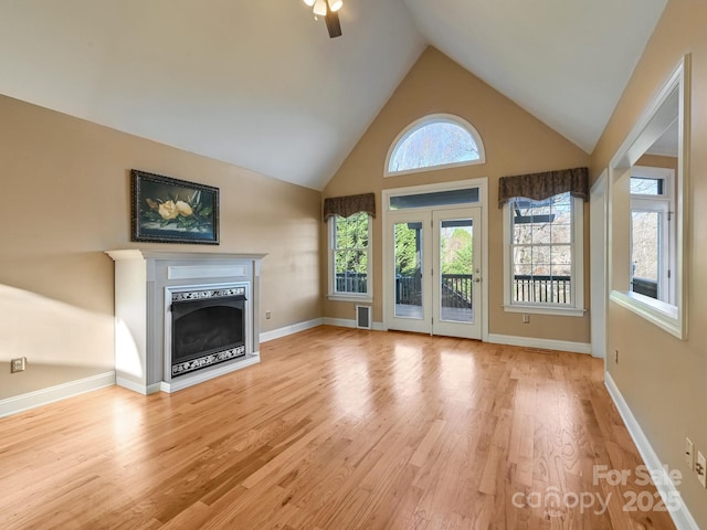 unfurnished living room with ceiling fan, high vaulted ceiling, and light hardwood / wood-style flooring