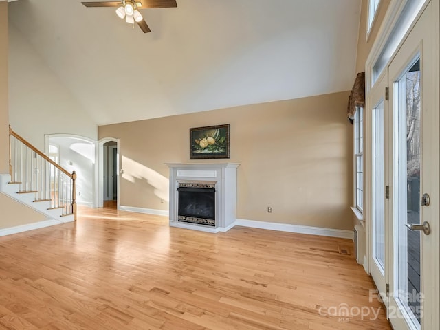 unfurnished living room with ceiling fan, high vaulted ceiling, and light wood-type flooring