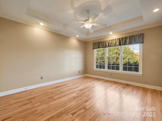 unfurnished room featuring a tray ceiling, crown molding, ceiling fan, and light hardwood / wood-style floors