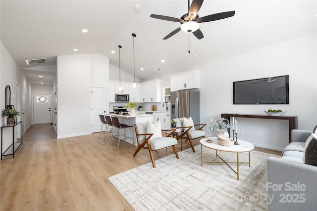 living room featuring ceiling fan, sink, high vaulted ceiling, and light hardwood / wood-style floors