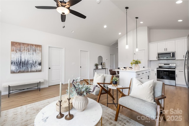 living room with ceiling fan, light hardwood / wood-style floors, and lofted ceiling