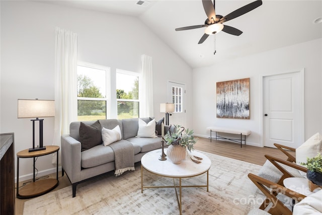 living room with ceiling fan, high vaulted ceiling, and light hardwood / wood-style flooring