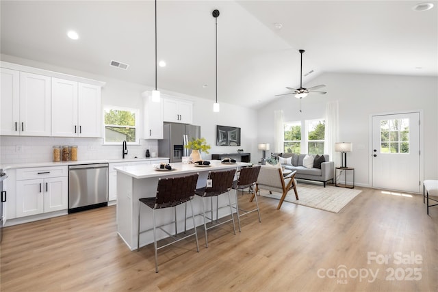 kitchen featuring a kitchen island, white cabinetry, backsplash, and appliances with stainless steel finishes