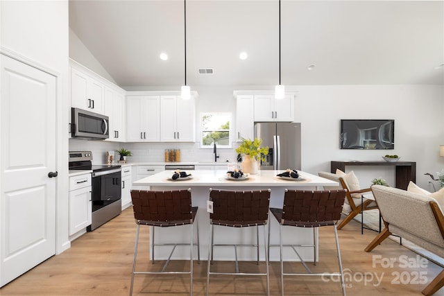 kitchen featuring decorative light fixtures, stainless steel appliances, white cabinetry, and sink