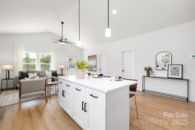 kitchen featuring white cabinetry, a center island, ceiling fan, pendant lighting, and a breakfast bar area